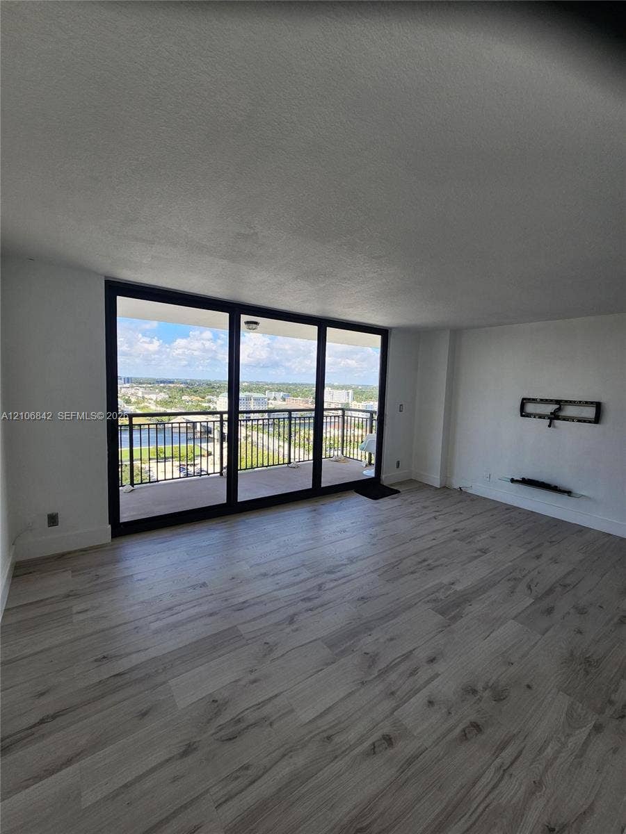 Living area featuring wood-finish flooring, floor-to-ceiling windows, and a private balcony with metal railing