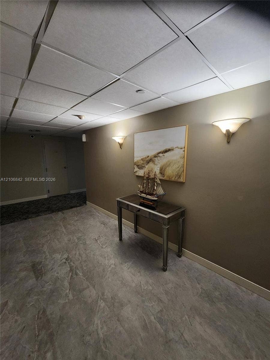 Large-format stone-tile flooring and recessed drop-ceiling grid with integrated wall-mounted sconce lighting