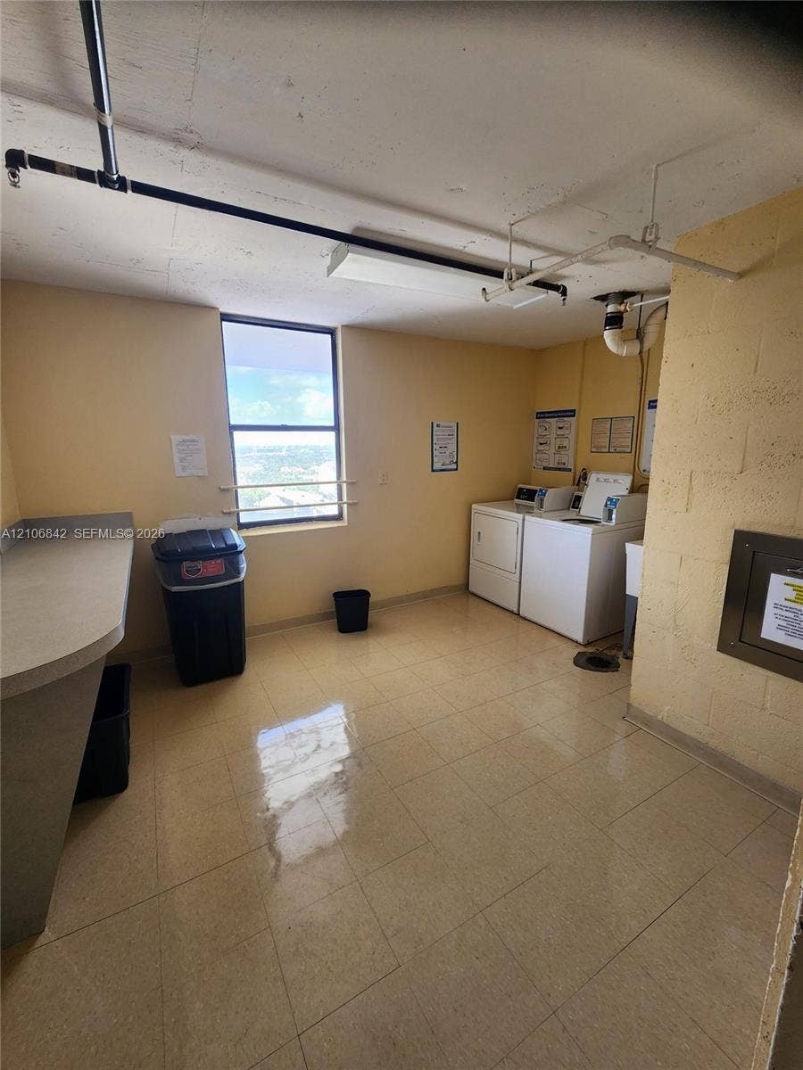 Laundry room featuring tile flooring, a dedicated workstation with a solid-surface countertop, and a window with exterior exposure