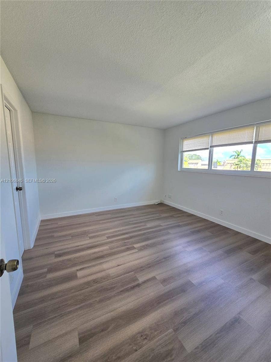 1700 NW 58th Terrace, #3J, Sunrise, Sunrise, FL 33313 Neutral-toned interior space featuring wood-finish flooring and a wide, multi-pane window