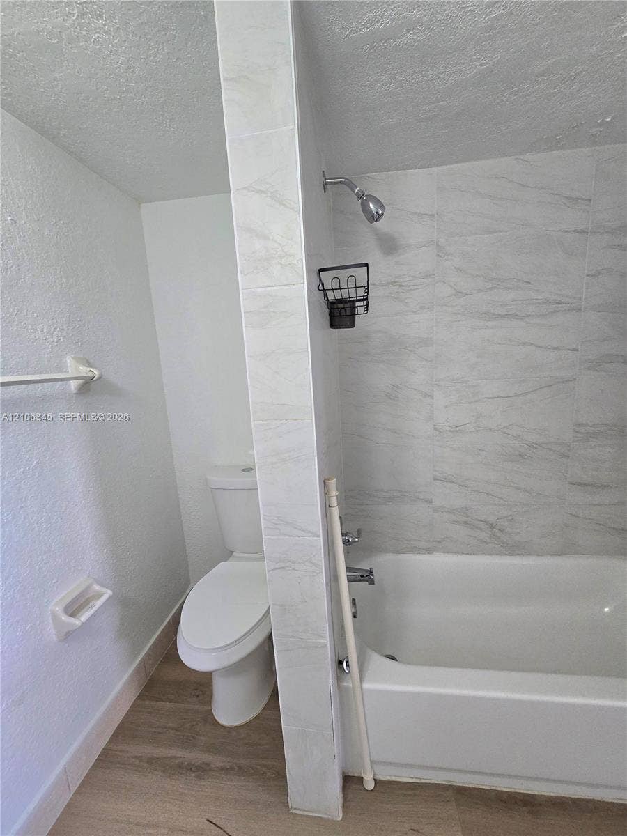 1700 NW 58th Terrace, #3J, Sunrise, Sunrise, FL 33313 Bathroom featuring a porcelain-tiled shower surround, integrated bathtub, wall-mounted toilet, and wood-finish flooring