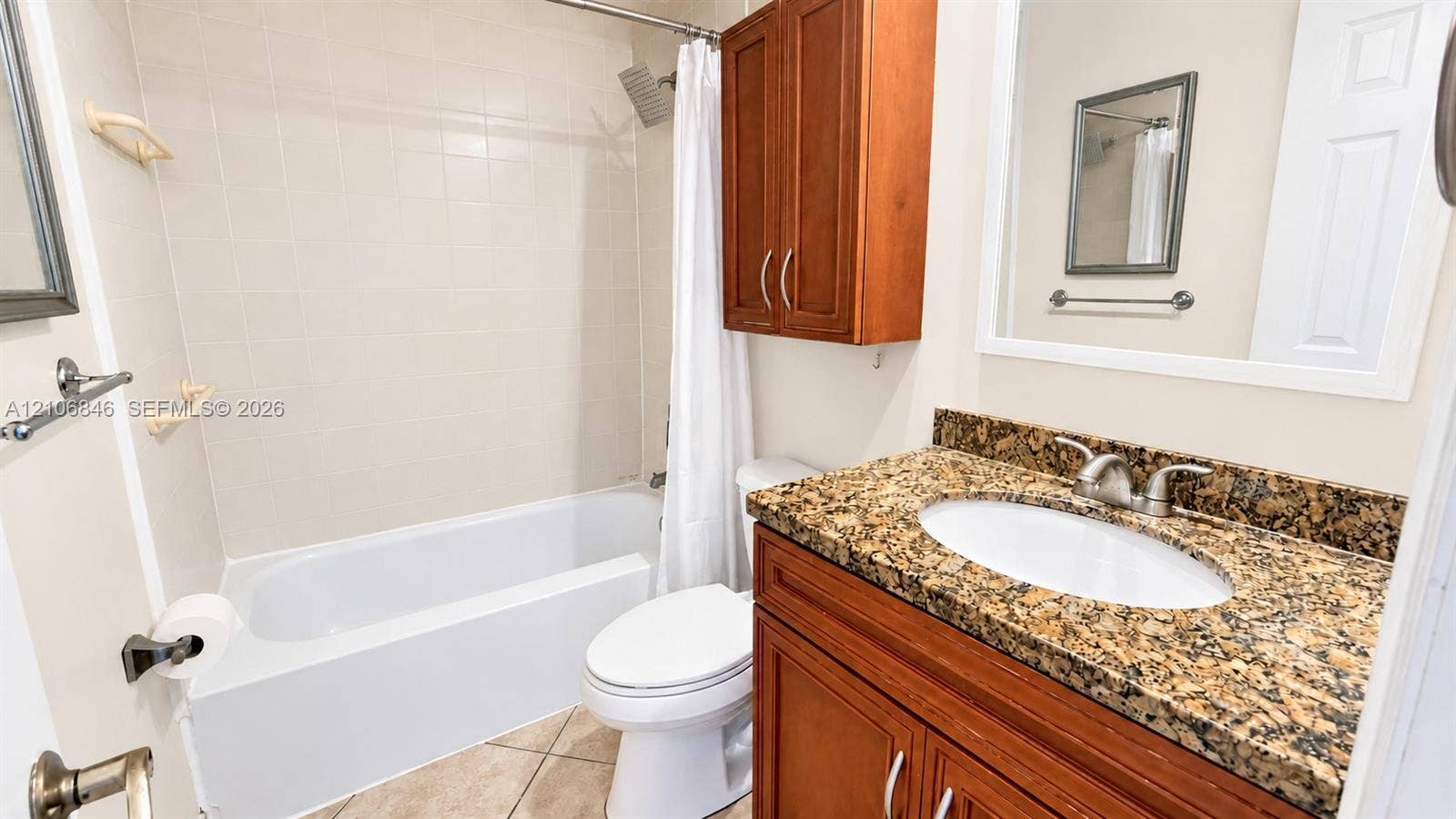 Bathroom featuring a stone-surface vanity with an integrated oval sink, wood-finish cabinetry, built-in wall storage, and a tiled tub and shower combination