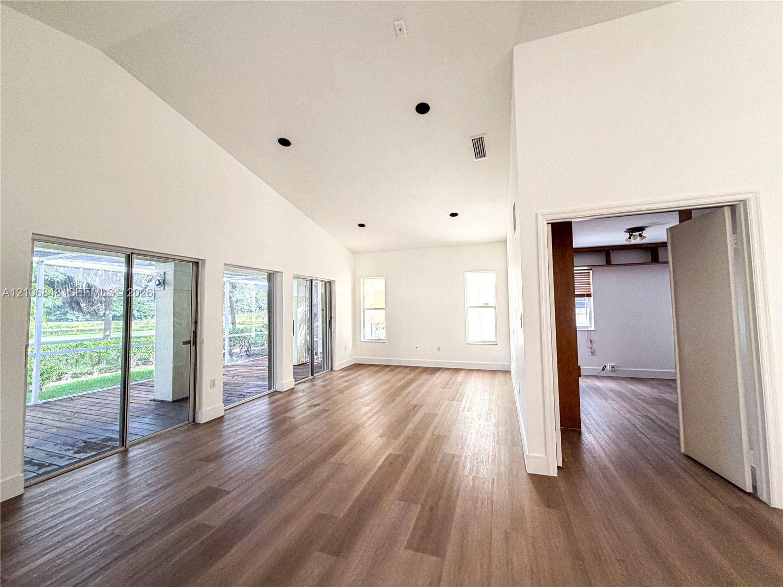 Vaulted ceilings, wood-finish flooring, recessed lighting, and expansive glass sliding doors