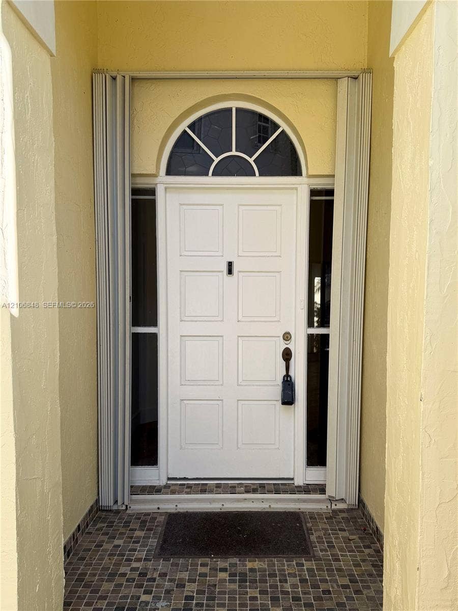 Entryway featuring a white eight-panel door, arched transom window, dual vertical sidelights, and a mosaic tile threshold