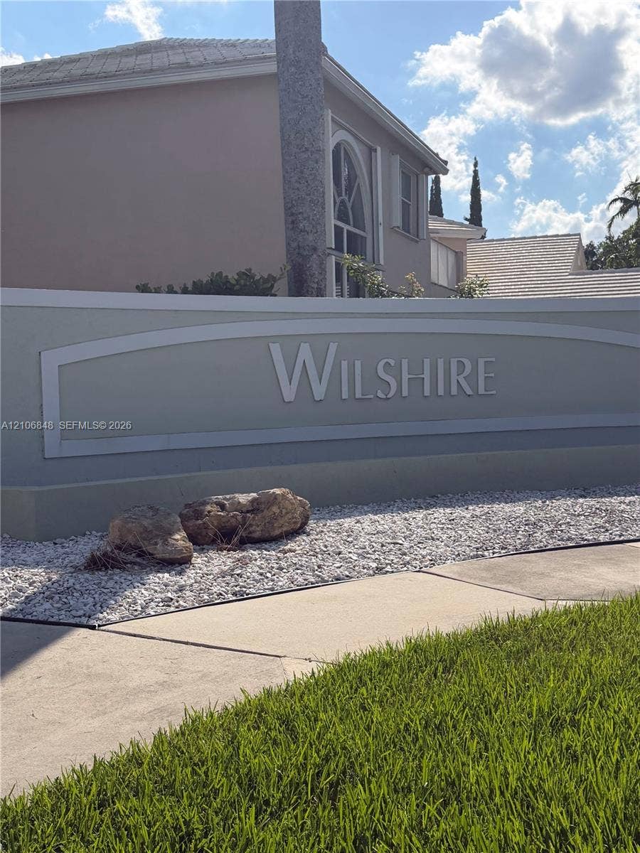 Stucco community monument sign featuring dimensional lettering, decorative stone accents, and manicured turf