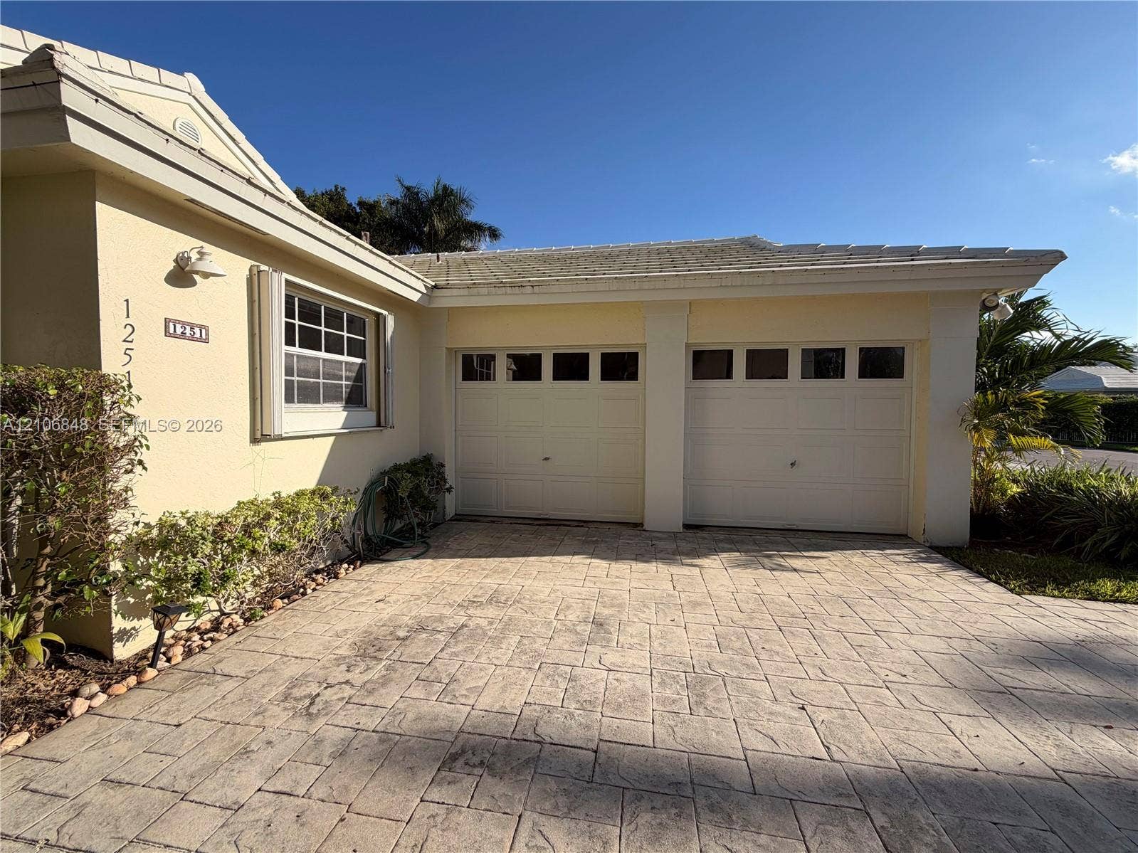 Stucco exterior featuring a two-car garage with paneled doors and a stamped concrete driveway