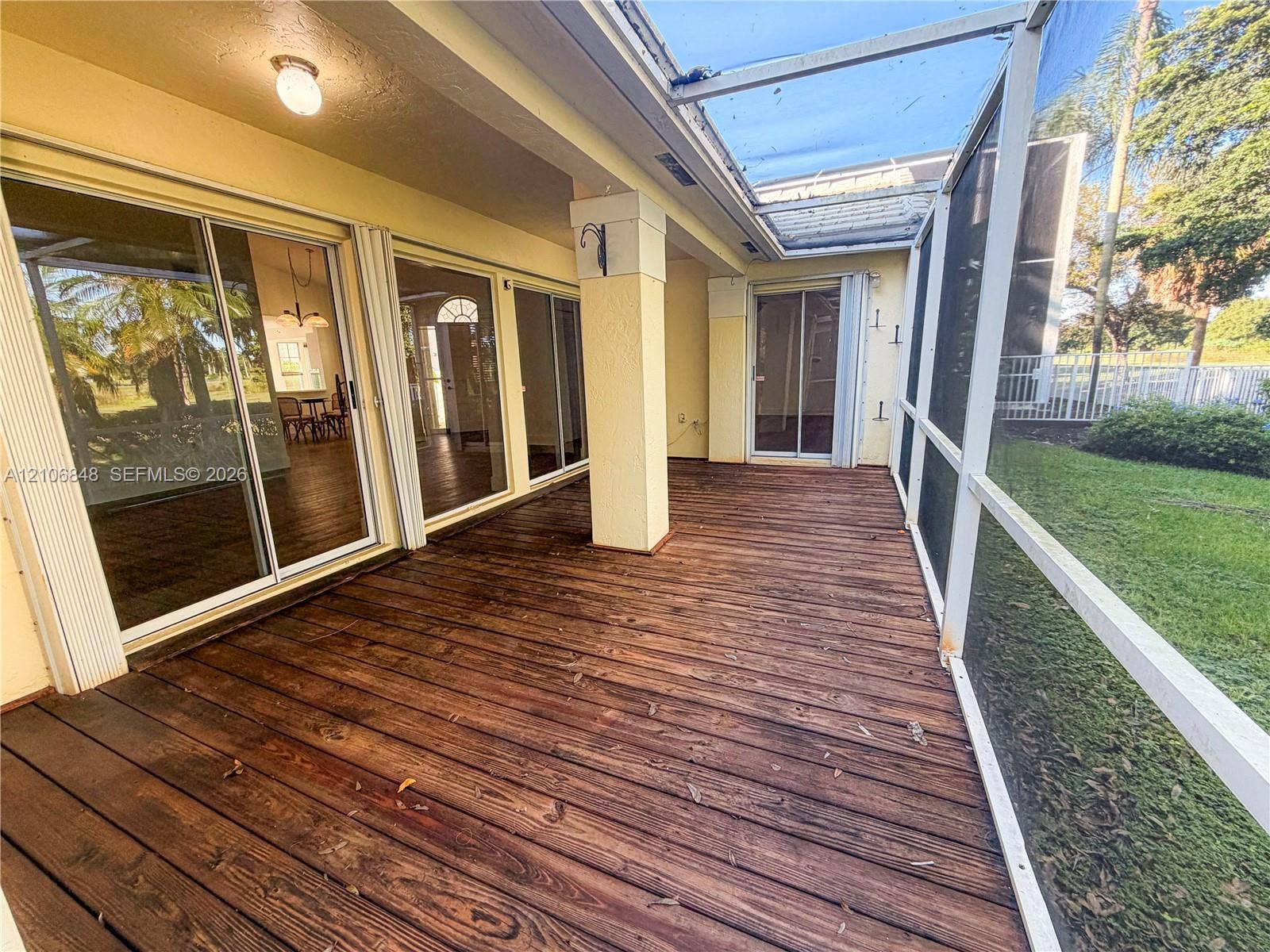 Screen-enclosed patio featuring a wood-plank deck, multiple sets of sliding glass doors, and recessed lighting
