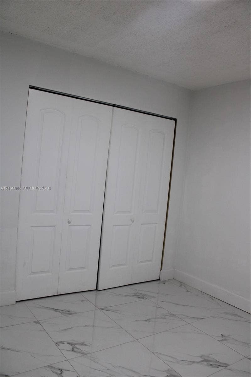 Large-format stone-patterned tile flooring and dual-panel white closet doors