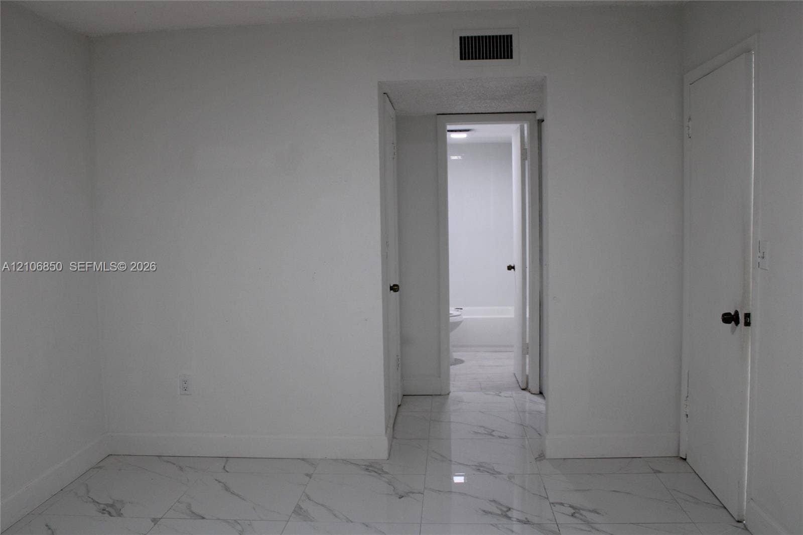 Polished large-format tile flooring with marble-finish detailing, solid-core interior doors, and neutral wall finishes