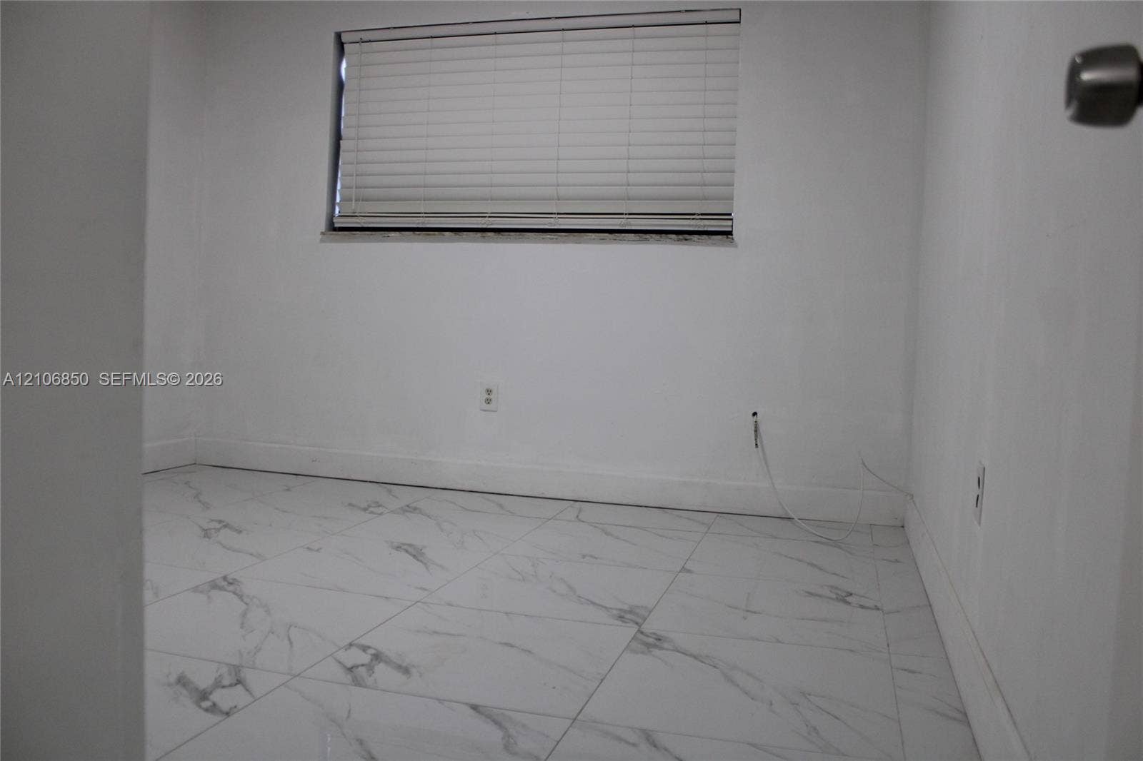 Interior space featuring white stone-finish tile flooring and an integrated horizontal window blind