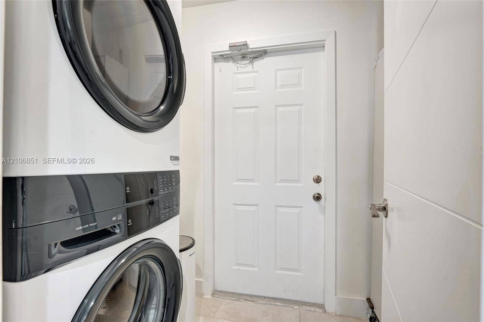 1319 SW 30th Street, #B, Fort Lauderdale, Fort Lauderdale, FL 33315 Stacked laundry unit with white finish and integrated control panels, six-panel interior door, and satin-finish metal hardware