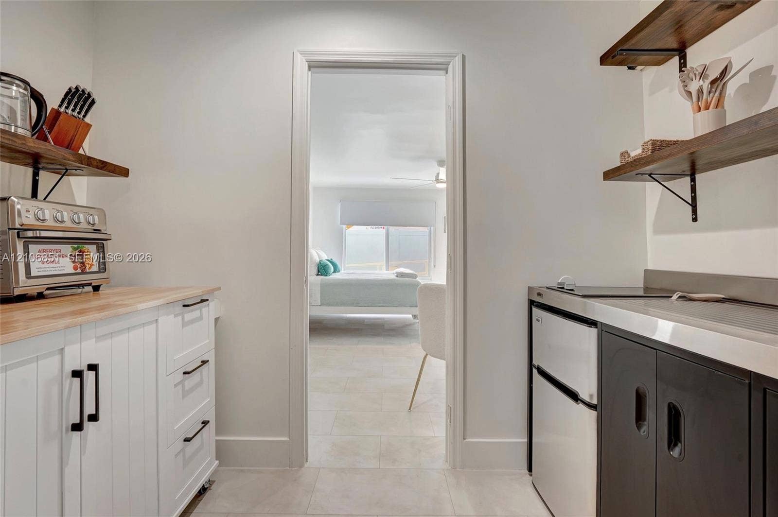 1319 SW 30th Street, #B, Fort Lauderdale, Fort Lauderdale, FL 33315 Kitchenette featuring white cabinetry with wooden countertops, dark lower cabinets with metal surfacing, and wall-mounted wooden shelving