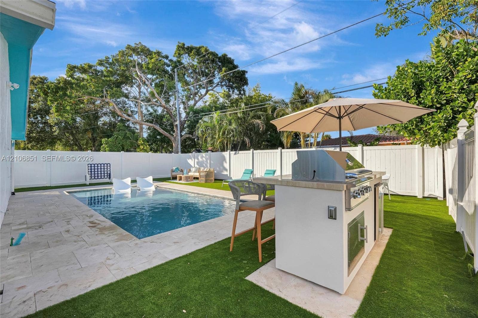 1319 SW 30th Street, #B, Fort Lauderdale, Fort Lauderdale, FL 33315 Backyard featuring an in-ground swimming pool, stone-paver decking, built-in outdoor kitchen with integrated grill, and synthetic turf lawn surrounded by white privacy fencing