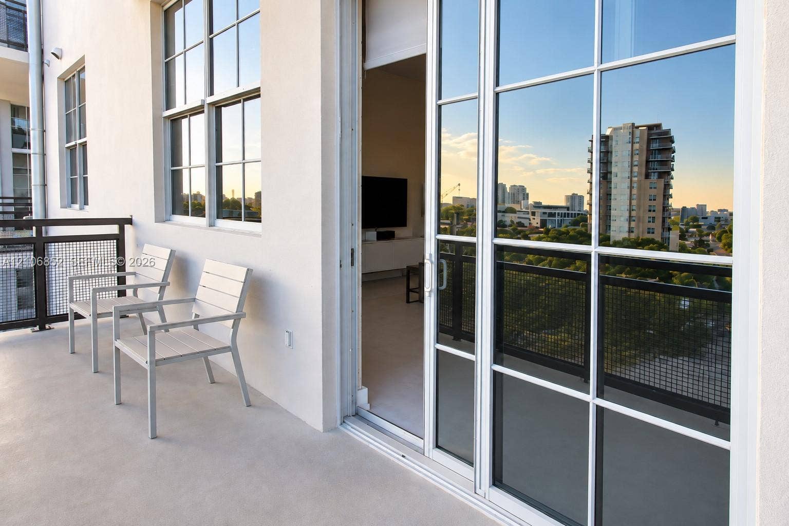 Covered balcony featuring a smooth surface, metal grid railing, and multi-pane glass sliding door