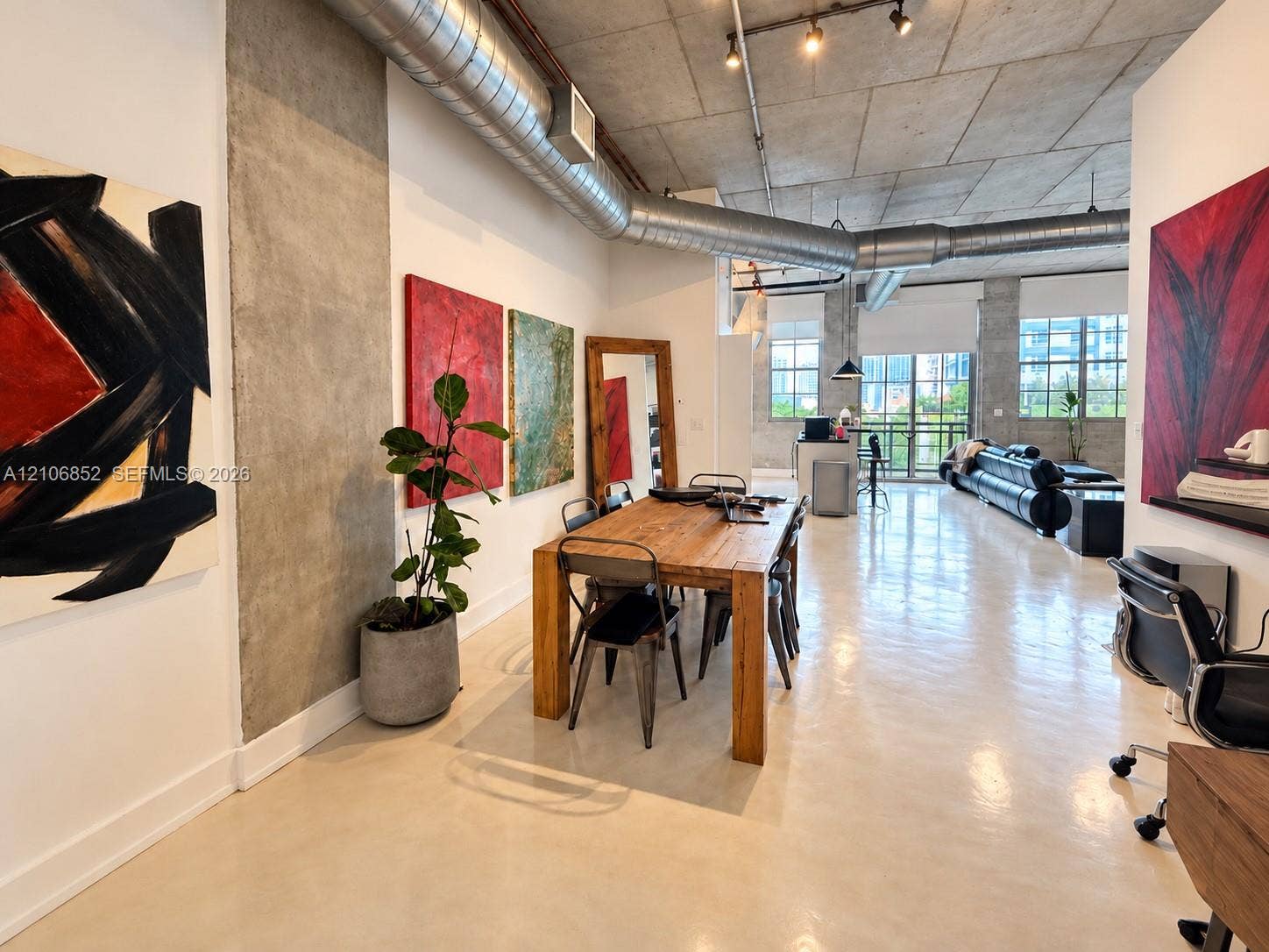 Industrial-style interior featuring exposed concrete ceilings, polished concrete flooring, exposed metal ductwork, and floor-to-ceiling windows