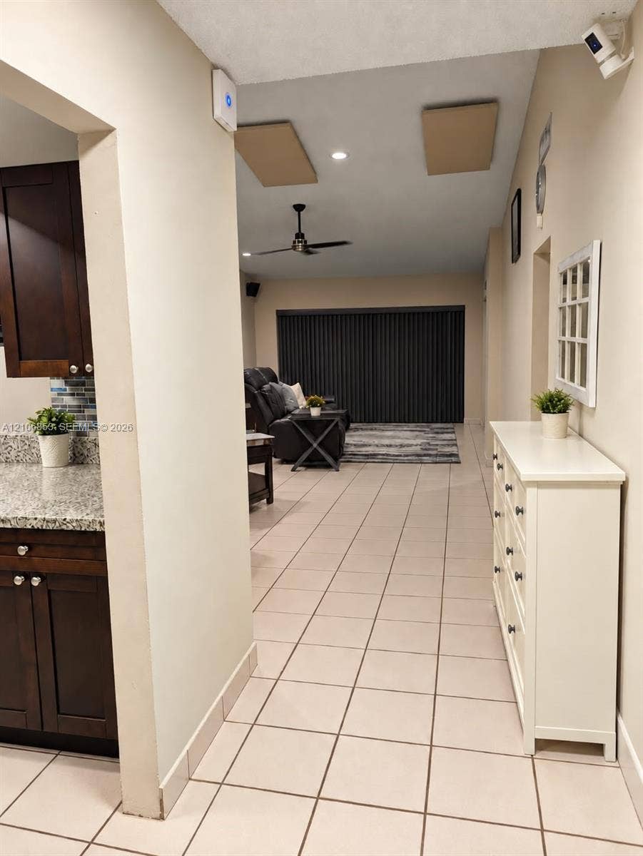 6331 Pinehurst Circle W, #C35, Tamarac, FL 33321 Kitchen featuring dark wood cabinetry, stone-finish countertops, and multi-colored glass tile backsplash, complemented by neutral tile flooring throughout the interior