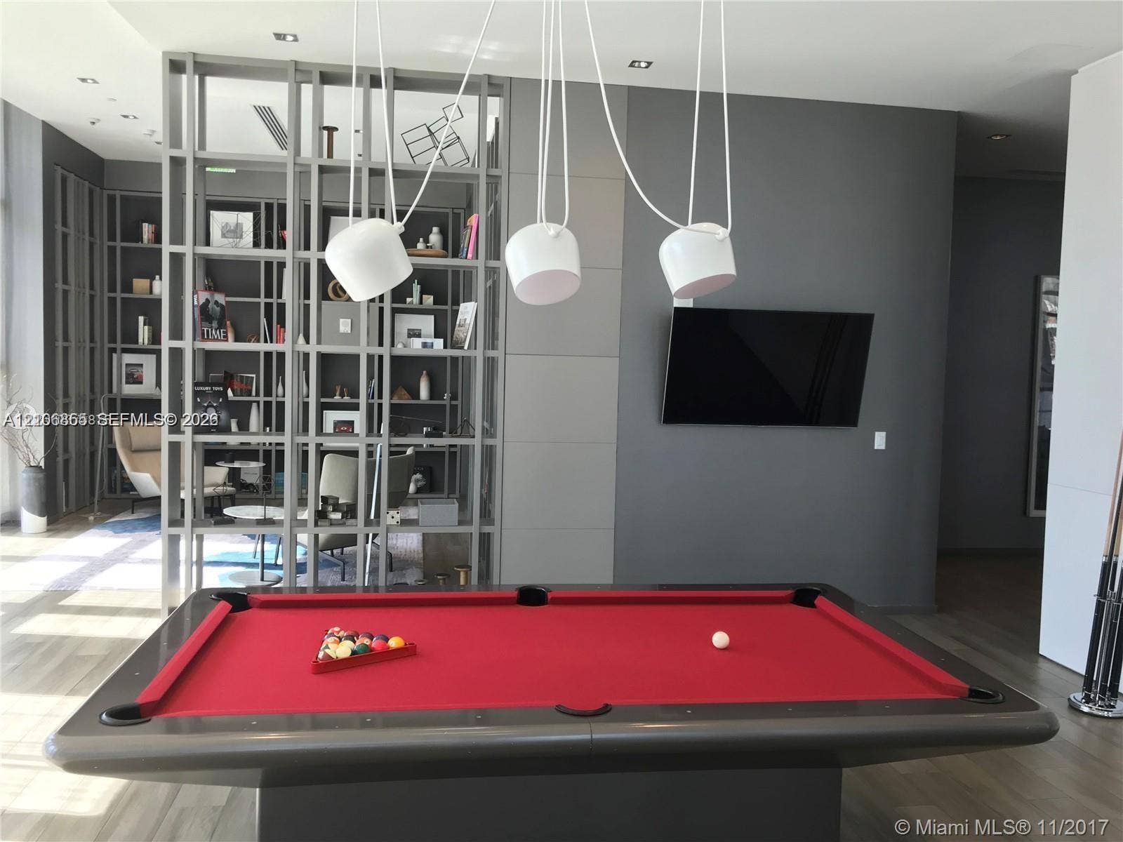 Custom floor-to-ceiling built-in shelving, wood-finish flooring, recessed ceiling lighting, and contemporary pendant fixtures