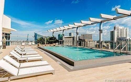 Rooftop swimming pool featuring a tile-finished deck, metal pergola, and perimeter glass railing