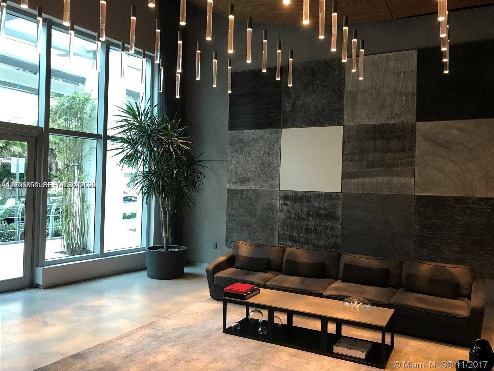 Floor-to-ceiling windows, custom grid-patterned wall texture, multi-pendant light installation, and tile flooring
