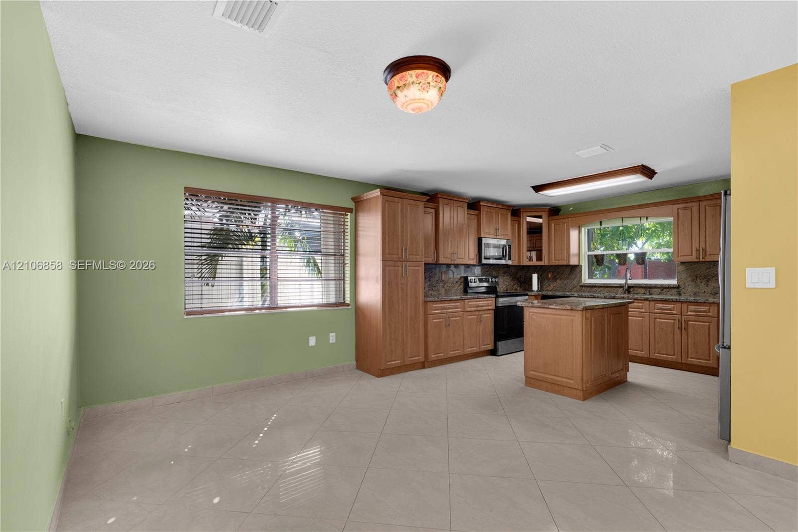 10960 SW 25th Street, Miami, FL 33165 Kitchen featuring wood cabinetry, stone countertops, central island, tile flooring, and integrated stainless steel appliances