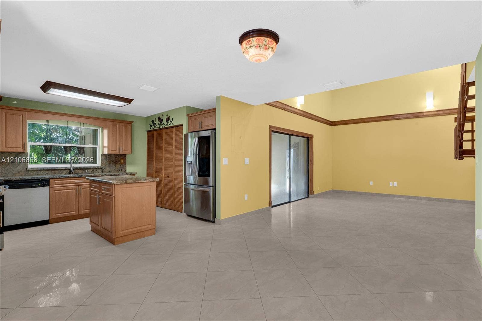 10960 SW 25th Street, Miami, FL 33165 Kitchen featuring natural wood cabinetry, stone countertops, central island, stainless steel refrigerator, and tiled flooring