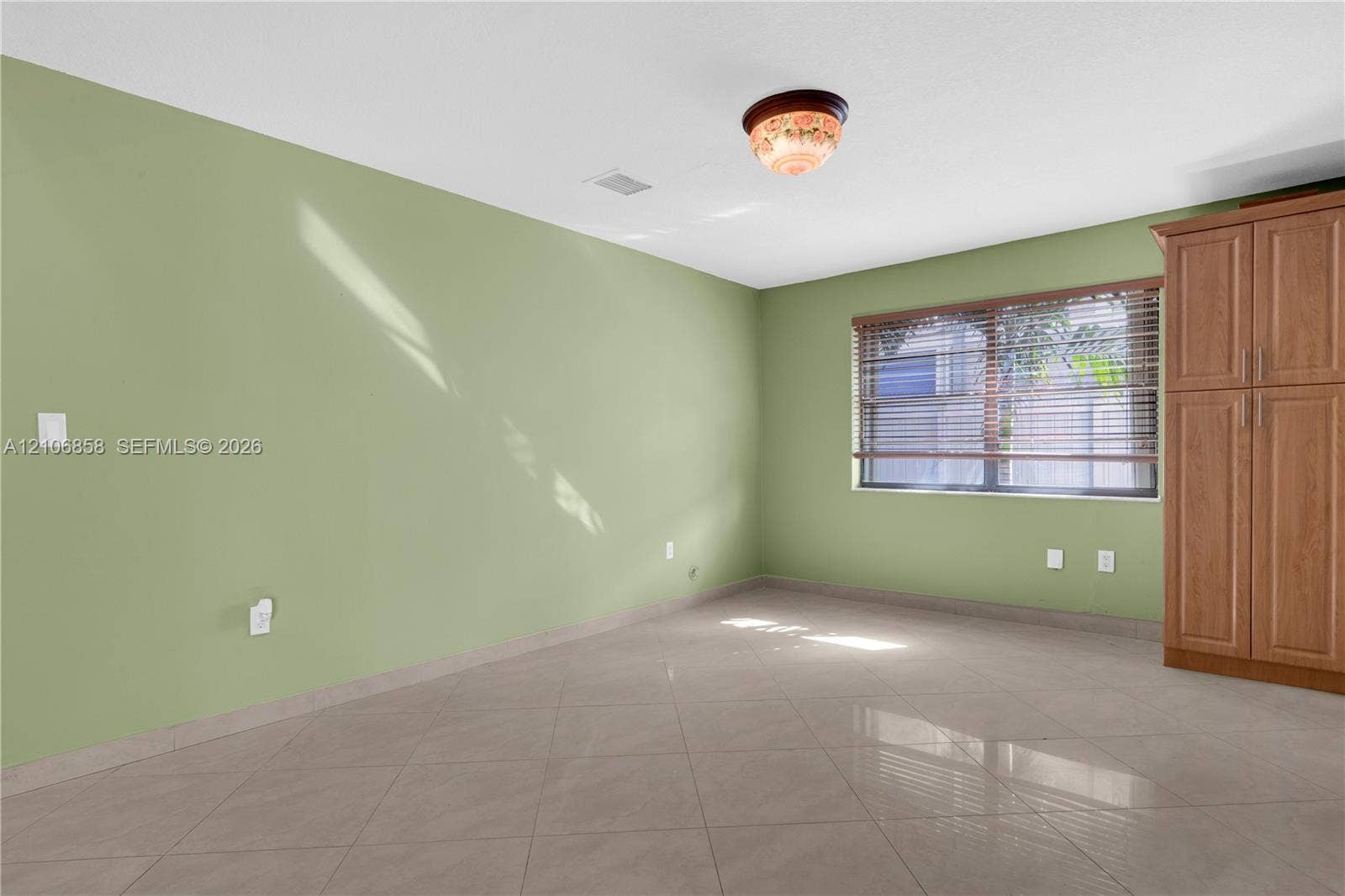 10960 SW 25th Street, Miami, FL 33165 Room featuring large-format tile flooring, built-in wooden cabinetry, and a window with horizontal blinds