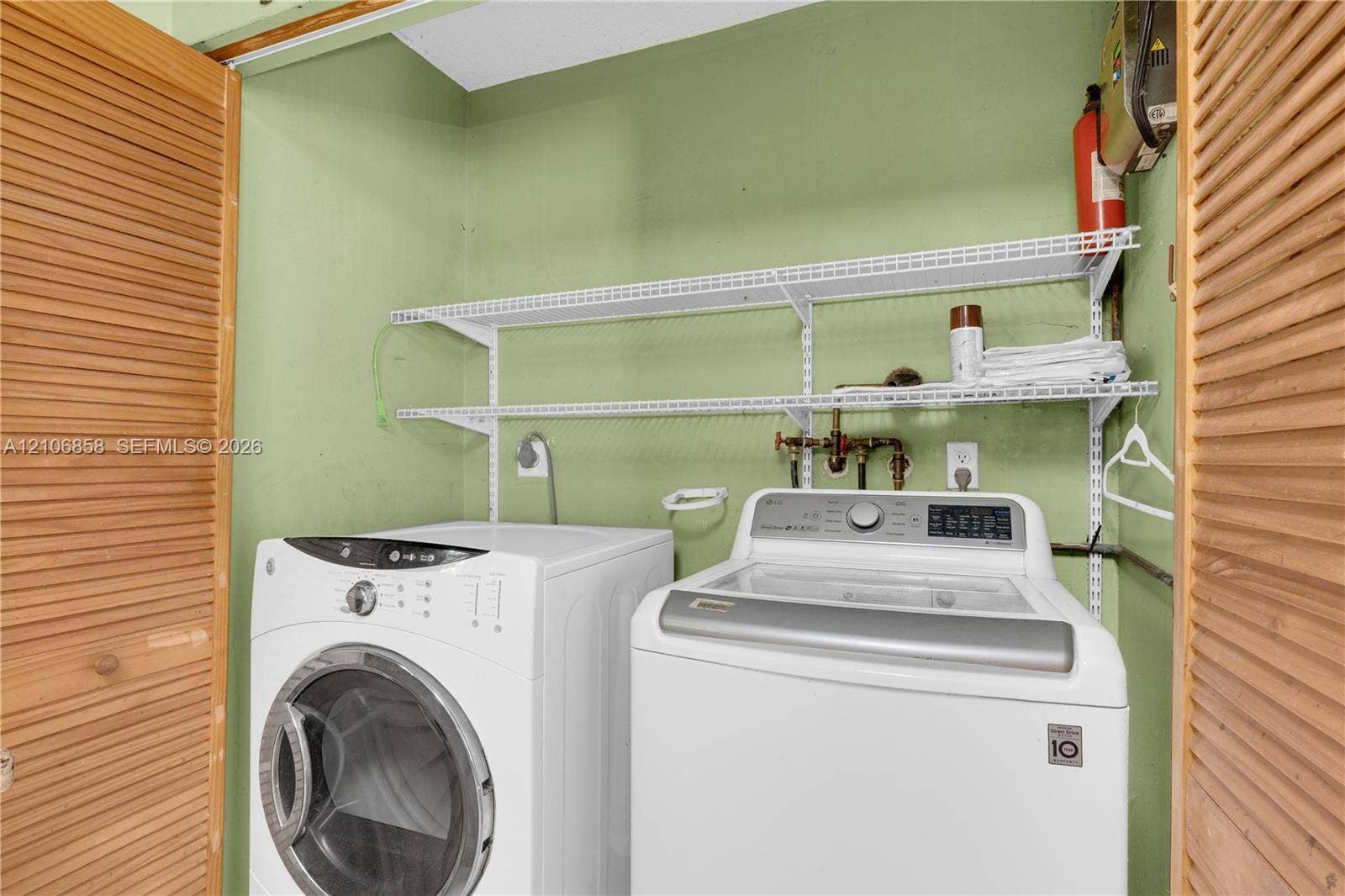 10960 SW 25th Street, Miami, FL 33165 Laundry area featuring dual louvered wood doors and two-tier wire shelving