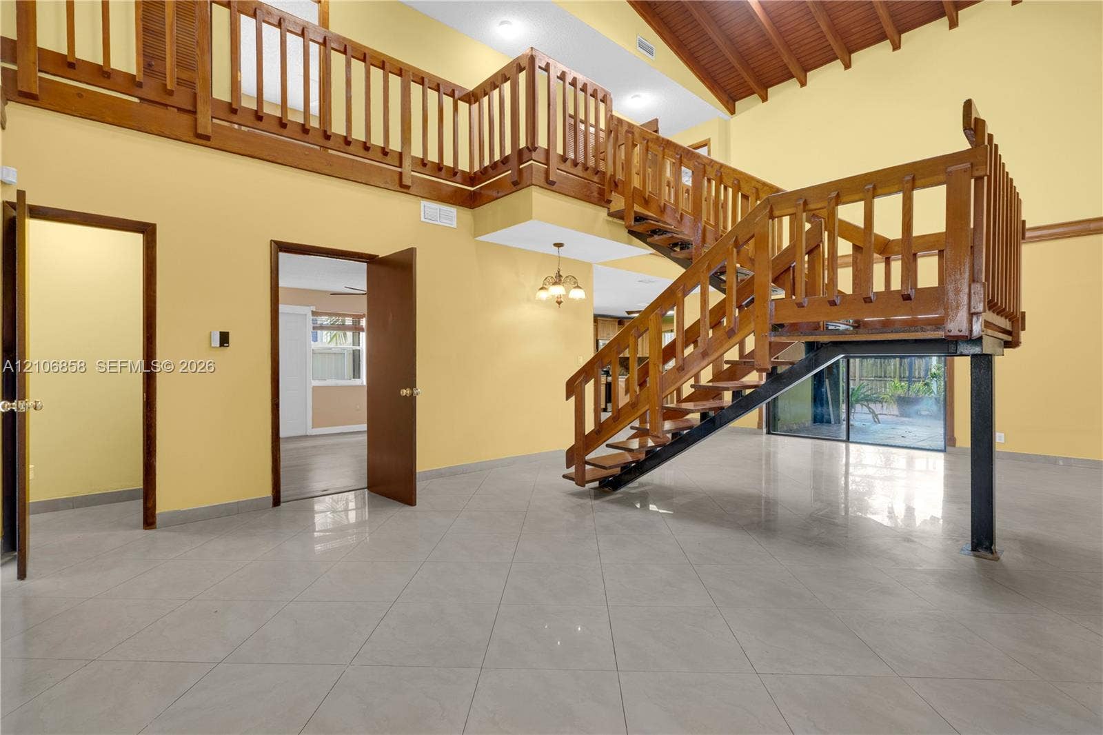 10960 SW 25th Street, Miami, FL 33165 Vaulted ceilings with exposed wooden beams, tile flooring, and a multi-level wooden staircase with balustrade railings