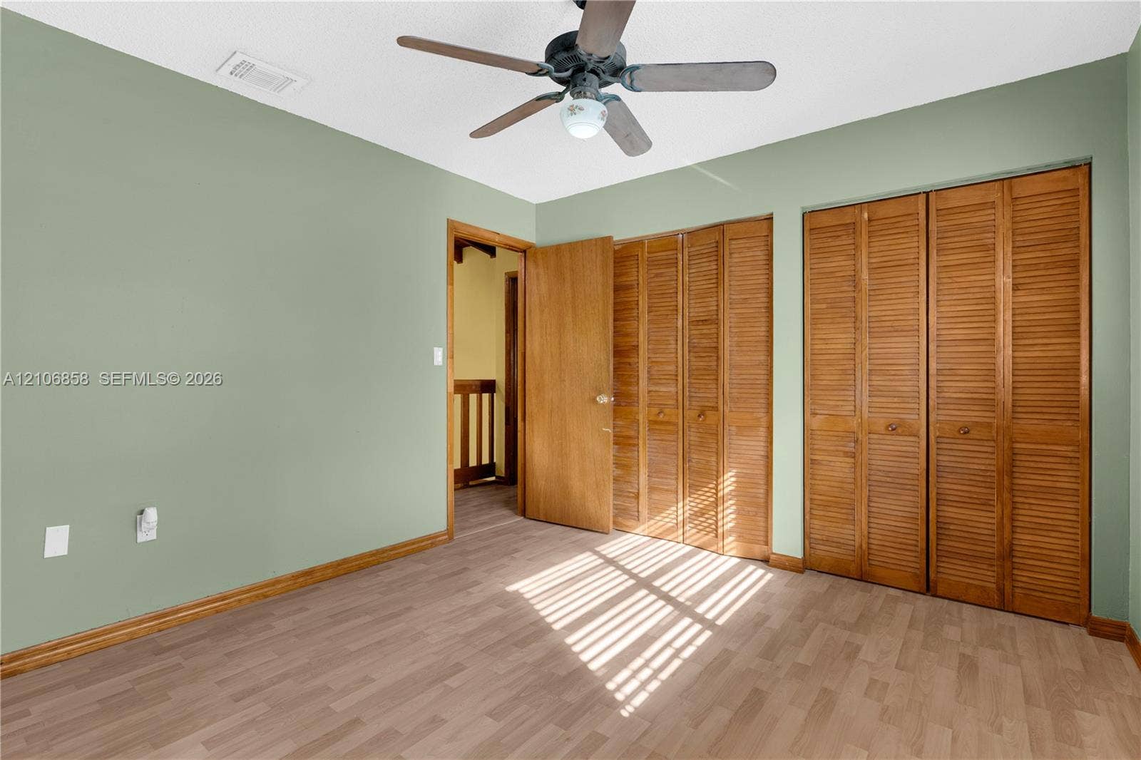 10960 SW 25th Street, Miami, FL 33165 Room featuring wood-finish flooring, dual bi-fold louvered closet doors, and a ceiling fan