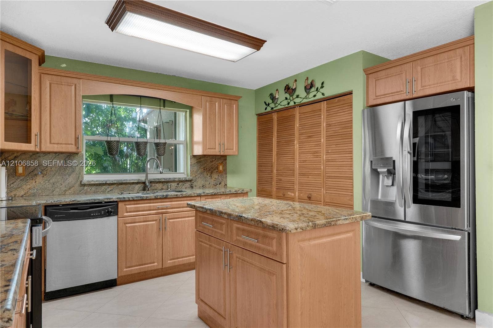 10960 SW 25th Street, Miami, FL 33165 Kitchen featuring natural wood cabinetry, stone-surface countertops, stainless steel appliances, a central island, and louvered built-in pantry doors