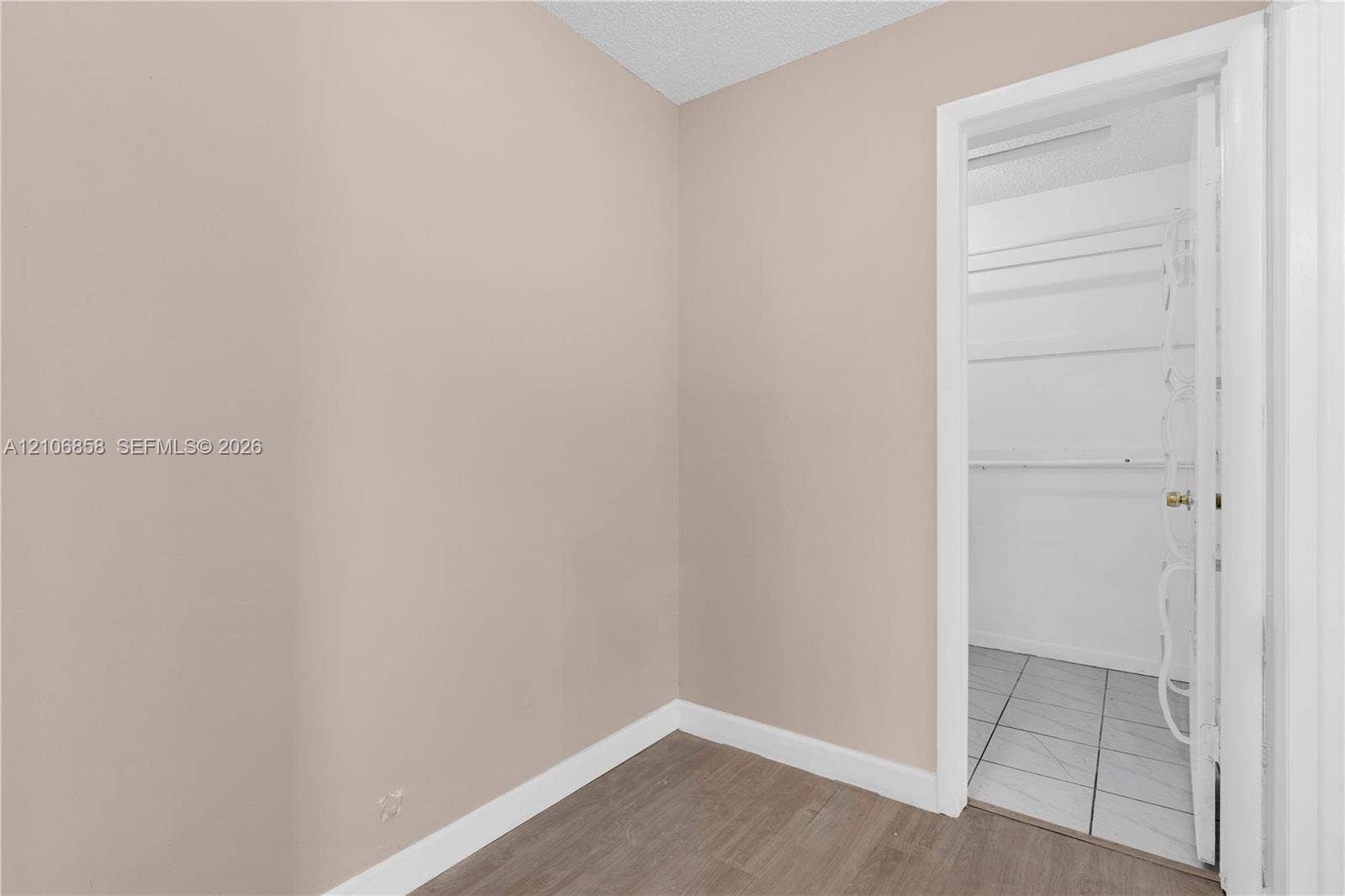 10960 SW 25th Street, Miami, FL 33165 Neutral-toned interior featuring wood-finish flooring, white door casing, and a reach-in storage area with built-in shelving and light-colored tile flooring