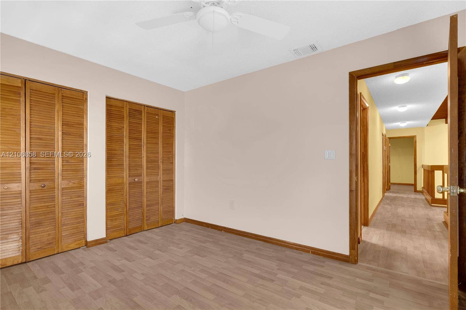 10960 SW 25th Street, Miami, FL 33165 Room featuring wood-finish flooring, dual closets with louvered doors, and a ceiling fan