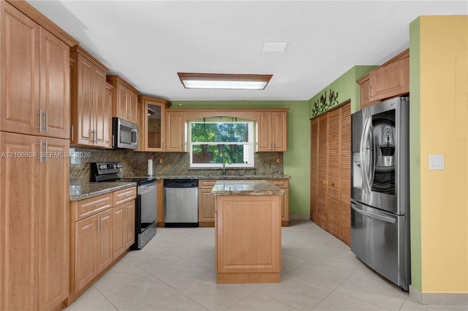10960 SW 25th Street, Miami, FL 33165 Kitchen featuring wood cabinetry, stone countertops, stainless steel appliances, a center island, and tile flooring