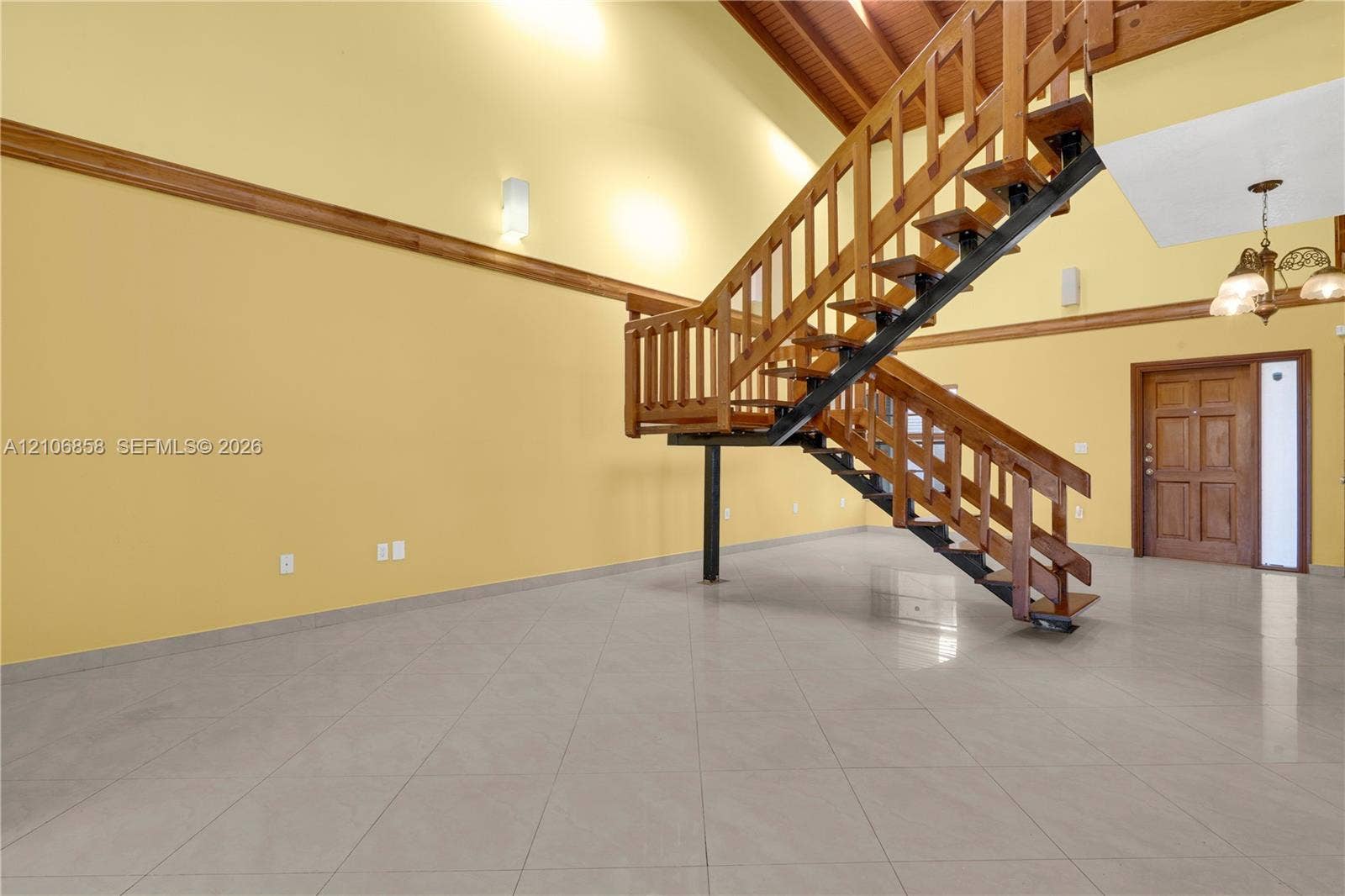 10960 SW 25th Street, Miami, FL 33165 Vaulted ceilings with exposed timber beams, open-concept staircase with wood railings and steel framing, ceramic tile flooring, and custom wood-paneled entry door