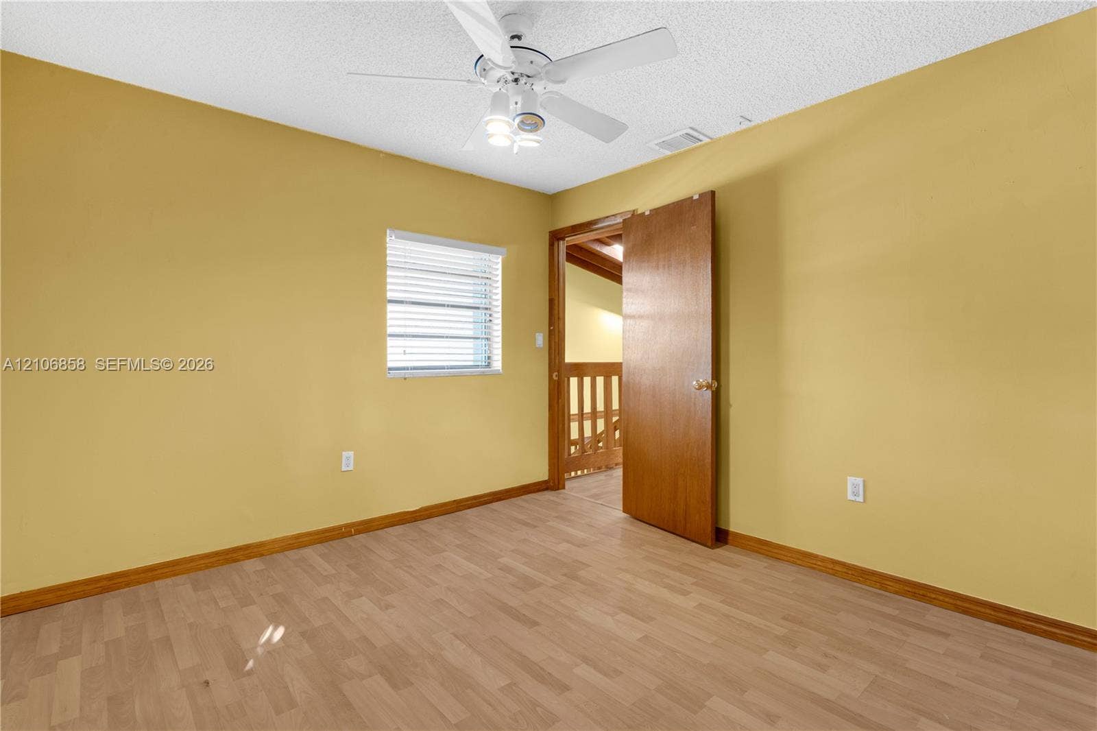 10960 SW 25th Street, Miami, FL 33165 Room featuring wood-finish flooring, a white ceiling fan with integrated lighting, and a window with horizontal blinds