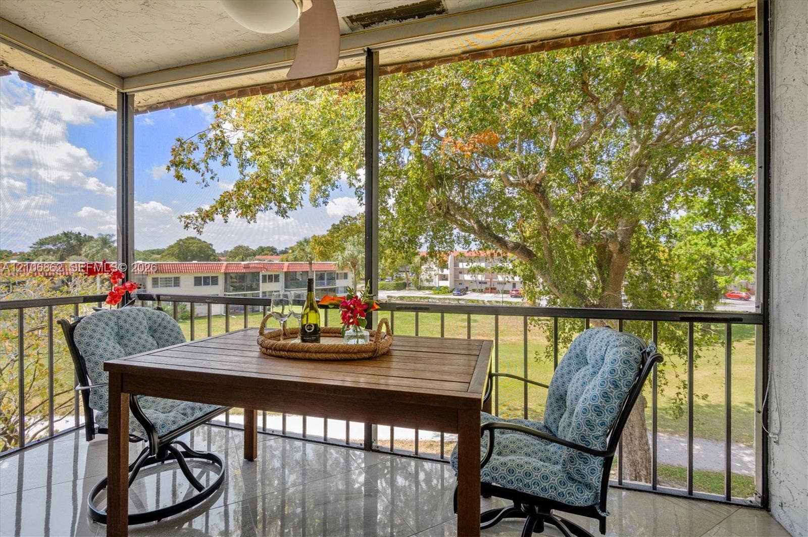 Screened balcony featuring tile flooring, metal railings, and a ceiling-mounted fan