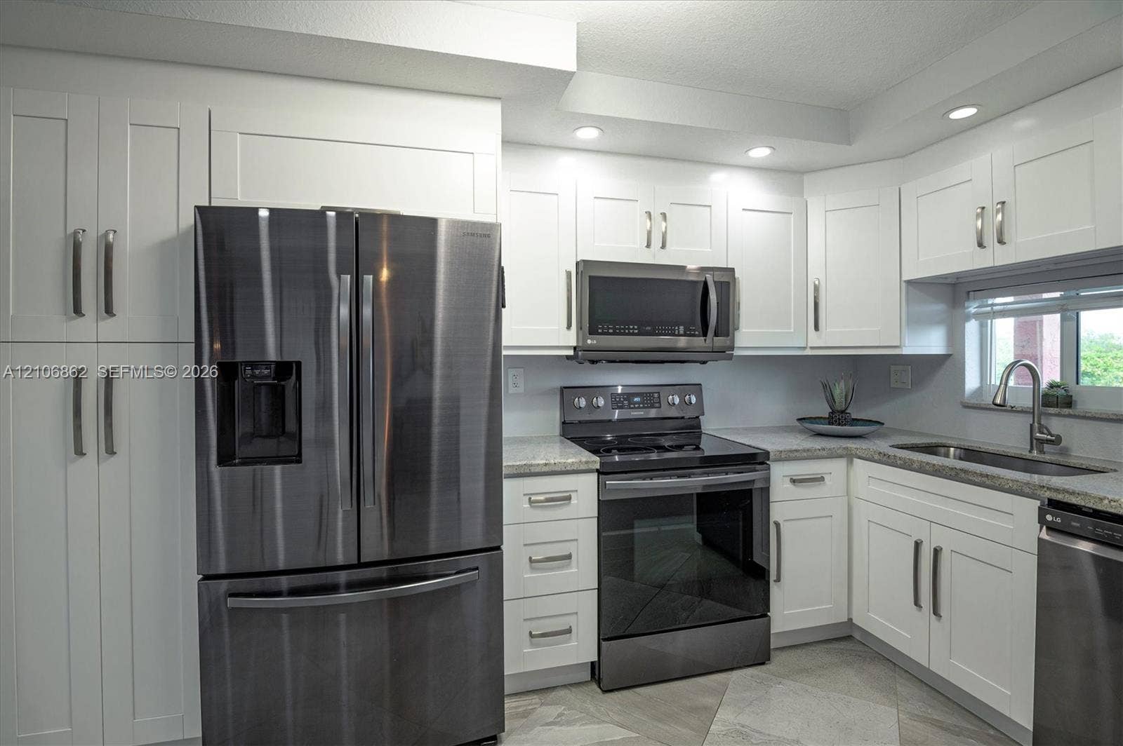 Kitchen featuring white shaker-style cabinetry, stainless steel appliances, speckled stone countertops, and recessed lighting