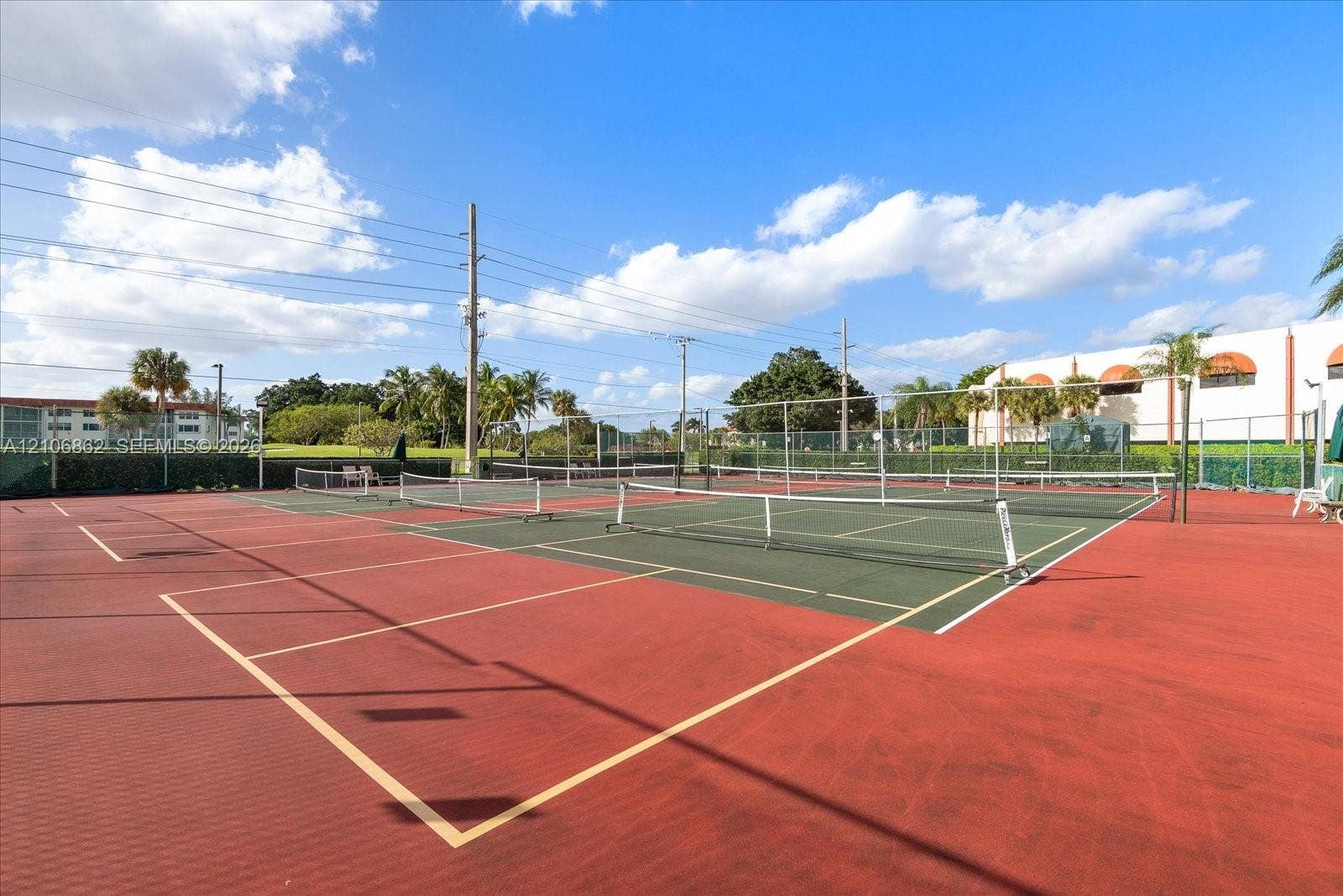 Multi-court tennis facility featuring surfaced playing areas, perimeter fencing, and net systems