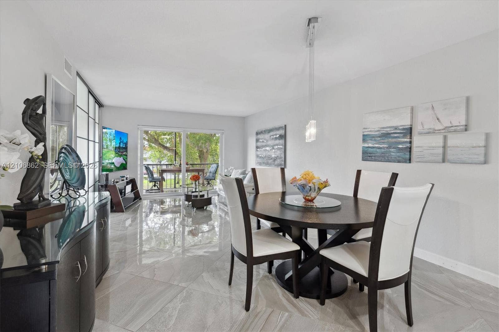 Open-concept area featuring polished tile flooring, sliding glass doors, and a modern pendant light fixture