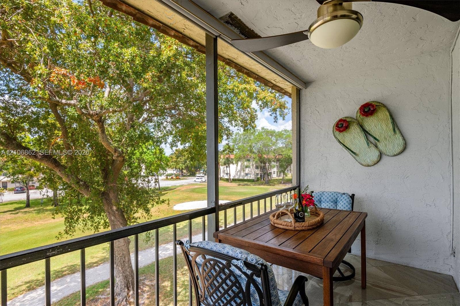 Screened balcony featuring a metal railing, stone-finish flooring, and a ceiling fan