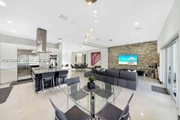 885 SW 144th Avenue, Miami, FL 33184 Open-concept living space featuring high-gloss cabinetry, stainless steel appliances, stone-veneer accent wall, and porcelain tile flooring