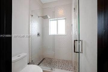 885 SW 144th Avenue, Miami, FL 33184 Walk-in shower with frameless glass enclosure, rainfall showerhead, mosaic stone flooring, and white tile surround