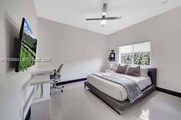 885 SW 144th Avenue, Miami, FL 33184 Neutral-toned interior featuring gloss-finish flooring, a multi-blade ceiling fan with integrated light, and a window with roller shade