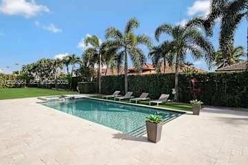 885 SW 144th Avenue, Miami, FL 33184 Rectangular swimming pool featuring stone paver decking, established palm trees, and a high perimeter hedge