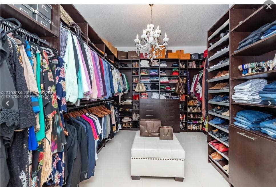 885 SW 144th Avenue, Miami, FL 33184 Walk-in closet featuring floor-to-ceiling built-in dark wood cabinetry, extensive shelving, integrated drawer storage, and a central chandelier fixture