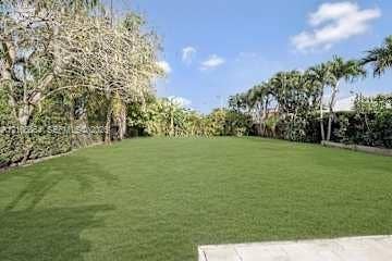 885 SW 144th Avenue, Miami, FL 33184 Expansive rear grounds featuring a manicured lawn, established perimeter hedges, and mature palm trees