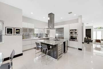 885 SW 144th Avenue, Miami, FL 33184 Modern kitchen featuring sleek flat-panel cabinetry, a central island with stone-finish countertops, stainless steel appliances, a chimney-style range hood, and polished flooring