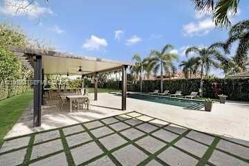 885 SW 144th Avenue, Miami, FL 33184 Outdoor living area featuring a covered pergola, concrete paver patio with grass joints, rectangular swimming pool, and privacy hedges