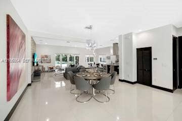 885 SW 144th Avenue, Miami, FL 33184 Open-concept interior featuring large-format tile flooring, a stone-accent wall, recessed lighting, and a crystal chandelier