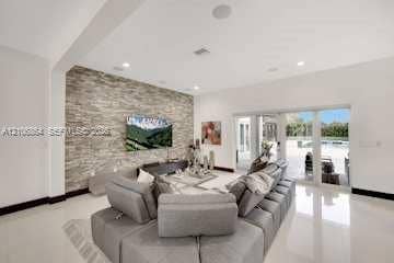 885 SW 144th Avenue, Miami, FL 33184 Living area featuring stacked stone accent wall, large-format tile flooring, recessed lighting, and multi-panel sliding glass doors
